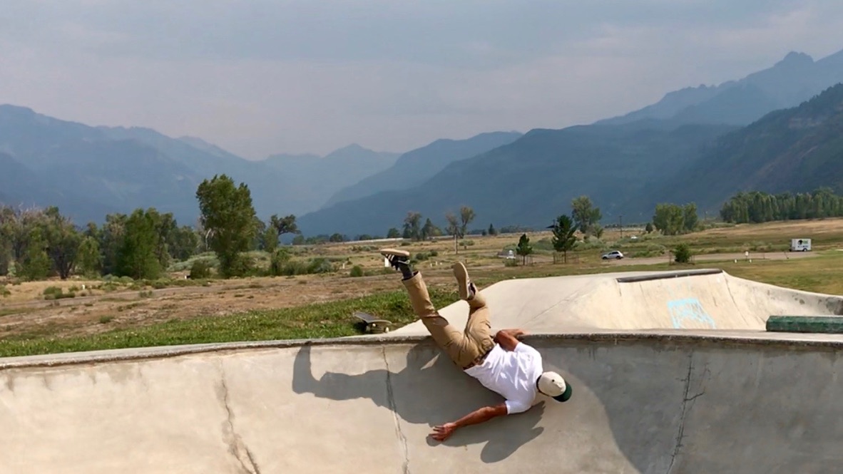 skateboarder falling on his face in a bowl with smoky mountains in the background